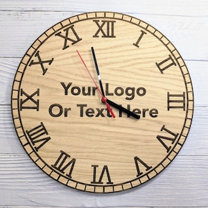 Peut inclure: Une horloge en bois avec des chiffres romains et une aiguille des heures et des minutes noire et rouge. Le cadran de l'horloge porte le texte "Your Logo Or Text Here" gravé.