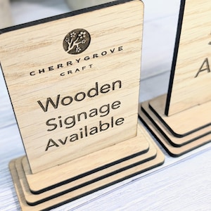 May include: Wooden sign with the text "Cherry Grove Craft" and "Wooden Signage Available". The sign is made of light brown wood and has a black border.