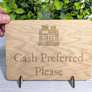 May include: A wooden sign with a cash register icon and the text "Cash Preferred Please".