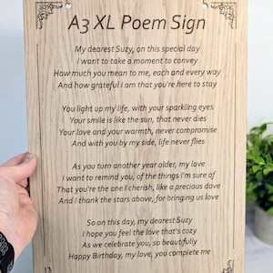 May include: A3 XL Poem Sign made of light-coloured wood, with a poem engraved in black. The sign has decorative corner designs and a jute twine hanger. The poem is addressed to Suzy and signed by Pete.