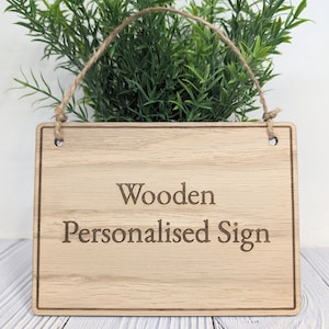 May include: A wooden sign with the text "Wooden Personalised Sign" engraved on it. The sign is hanging from a twine string.