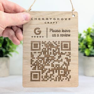 Könnte beinhalten: Rechteckiges Holzschild mit der Aufschrift "CHERRYGROVE CRAFT" und "Please leave us a review". Es zeigt einen QR-Code, ein Google-Logo mit fünf Sternen und eine Schlaufe aus Naturfaser zum Aufhängen.