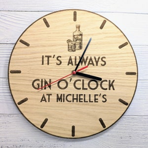 May include: A wooden clock with a red and black hand. The clock face has the text "It's always gin o'clock at Michelle's" and a graphic of a bottle of gin and a glass.