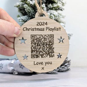 May include: A wooden Christmas bauble ornament with a QR code, the text "2024 Christmas Playlist", and the words "Love you" with a handwritten "x".