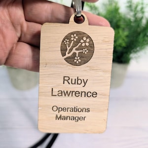 May include: A wooden name tag with a cherry blossom design. The name tag reads "Ruby Lawrence, Operations Manager".