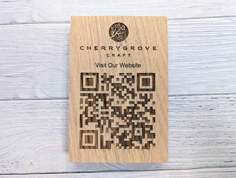 Op de afbeelding: Houten bord met de tekst "Cherry Grove Craft" en een gestileerd boomlogo. Het bord bevat ook een QR-code met de tekst "Bezoek onze website".