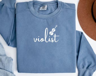 May include: A blue sweatshirt with a white graphic of a violin and the word "violist" on the front.