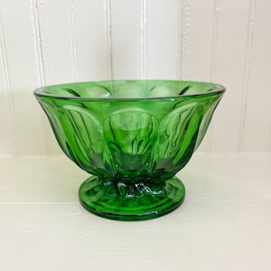 May include: A green glass bowl with a fluted design and a pedestal base.