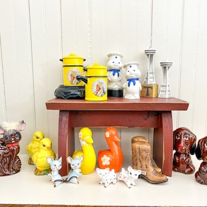 May include: A collection of vintage salt and pepper shakers, including a pair of yellow ducks, a pair of brown dogs, a pair of brown bunnies, a pair of yellow chickens, a pair of cowboy boots, a pair of white chefs, a pair of yellow canisters, and a pair of space needle shakers.