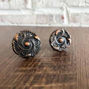 May include: Two ornate, copper-toned drawer pulls with a swirling, floral design.