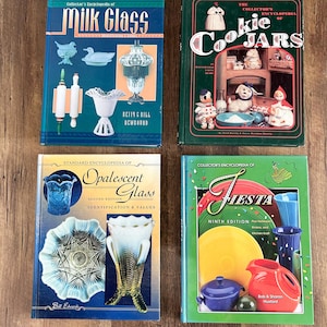 May include: Four vintage collector's books on a wooden surface. Titles include "Milk Glass", "Cookie Jars", "Opalescent Glass", and "Fiesta". The books feature colorful covers with illustrations of glassware and collectibles.