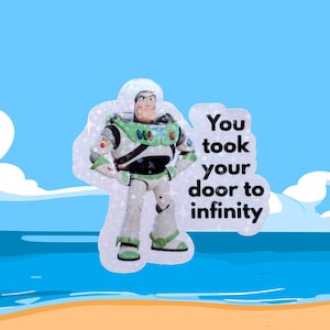 May include: A sticker of Buzz Lightyear in a spacesuit, with the text "You took your door to infinity". The background shows a blue sky, sea, and a sandy beach. The character is in green, white, and black.
