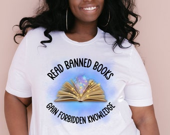 Könnte beinhalten: Weißes T-Shirt mit einem Grafikdruck eines offenen Buches mit leuchtenden Lichtern und dem Text "Read Banned Books Gain Forbidden Knowledge".