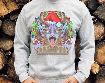 May include: A gray sweatshirt with a colorful illustration of Krampus, a Christmas demon, wearing a Santa hat and holding a sign that says "Krampus".