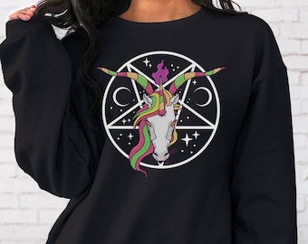 Peut inclure: Sweat-shirt noir avec un pentagramme blanc et une tête de licorne arc-en-ciel à l'intérieur. La licorne a une crinière et une corne rose, jaune et verte.