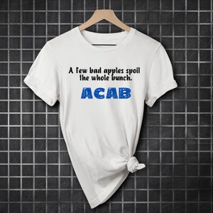 Puede incluir: Camiseta blanca con el texto "A few bad apples spoil the whole bunch. ACAB" impreso en negro y azul.