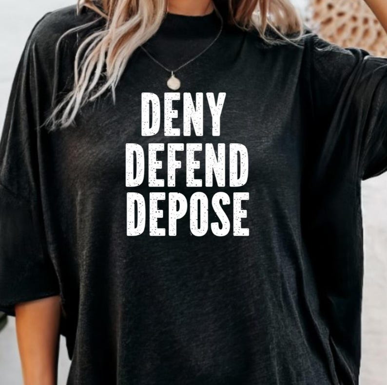 May include: Black oversized t-shirt with the text "DENY DEFEND DEPOSE" printed in white.