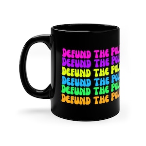 May include: Black coffee mug with the phrase "DEFUND THE POLICE" repeated in rainbow colours.