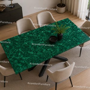 Può includere: Un tavolo da pranzo rettangolare con una superficie verde vibrante e strutturata, sostenuto da una base nera. Quattro sedie imbottite beige circondano il tavolo. Un vaso nero con verde e una ciotola nera sono sul tavolo. Il testo "KcomfortFurniture" è visibile.