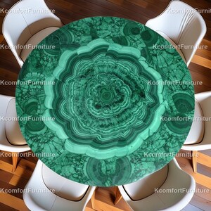 Op de afbeelding: Een ronde tafel met een blad van malachietsteen, met concentrische patronen in groen- en donkergroentinten. De tafel wordt omringd door witte stoelen, wat een moderne eethoek creëert.