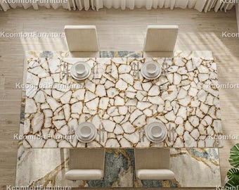 Puede incluir: Vista aérea de una mesa de comedor rectangular con una superficie de mosaico blanco y dorado. Cuatro sillas beige rodean la mesa, cada una con un plato blanco, cubiertos y una taza. La mesa descansa sobre una alfombra estampada.