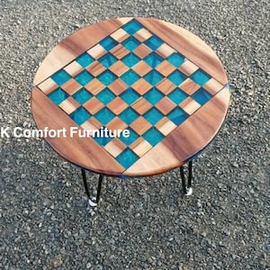 May include: Round wooden table with a turquoise and wood checkered top. The table has black hairpin legs. The table is approximately 24 inches in diameter.