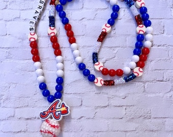 May include: A red, white, and blue beaded lanyard with a baseball charm and a silver key chain. The beads are interspersed with baseballs and the letters "GO BRAVES".