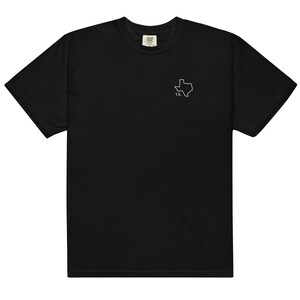 Może przedstawiać: Czarny T-shirt z białym obrysem stanu Teksas i skrótem "TX" poniżej.