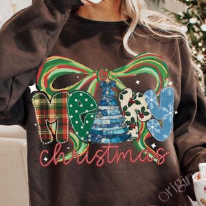 May include: A brown sweatshirt with a colorful "Merry Christmas" graphic. The graphic features a plaid "M", a green polka dot "E", a blue and white Christmas tree, and a blue "Y". The word "Christmas" is in red script.