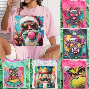 Puede incluir: Una colección de camisetas coloridas con temática navideña. Una camiseta presenta a Papá Noel con gafas de sol y una burbuja de chicle. Otras camisetas muestran una vaca de las Highlands, un árbol de Navidad, un cascanueces y el Grinch.