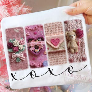 以下が含まれることがあります： ニットのデザインが施された4つの長方形のパネルが付いた白い生地。パネルには、花束、ハート型の箱、ハートの付いた封筒、ハート型の風船を持ったテディベアが表示されています。「xoxo」という言葉は黒い筆記体で書かれています。