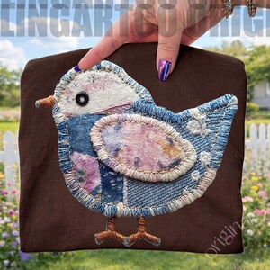 May include: A brown fabric item featuring a blue bird applique. The bird is made of denim and floral fabric patches, with a white head and a black eye. The bird has brown stitched feet and a brown beak. The background includes text that reads "FeelingArtCo Original".