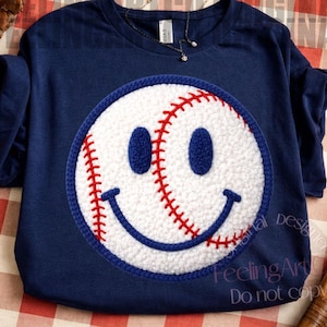 May include: Navy blue sweatshirt featuring a baseball smiley face design. The smiley face is white with red stitching and blue accents. The shirt has a crew neck and long sleeves. The text "FeelingArt" and "Do not copy" are visible on the bottom right.
