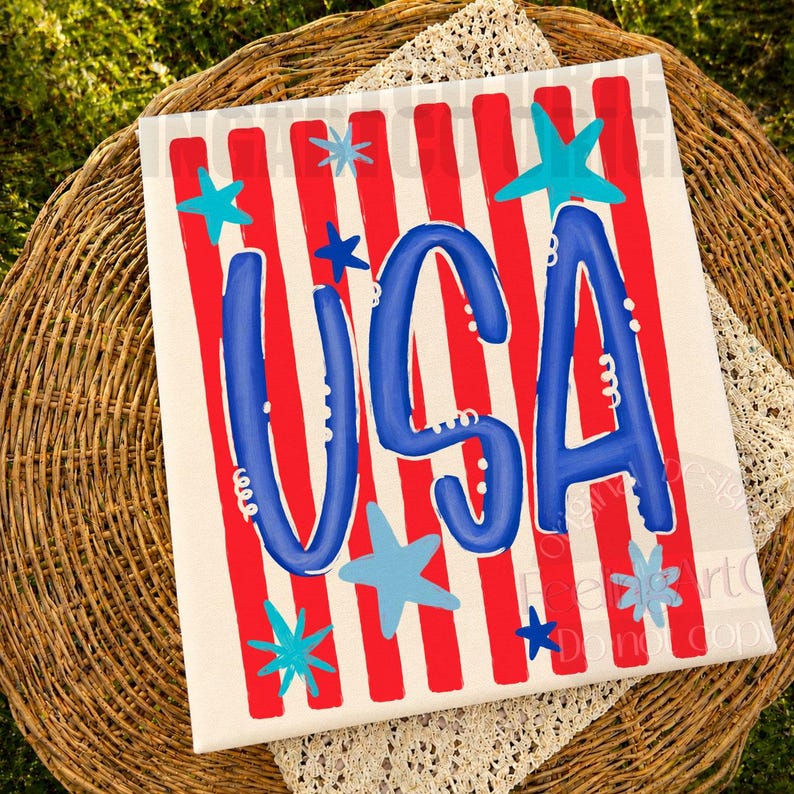 May include: A patriotic canvas art piece with a red and white striped background. The word "USA" is prominently displayed in blue, accented by blue stars. The artwork is placed on a woven basket with a lace trim.