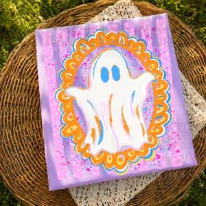 May include: A rectangular canvas painting featuring a central white ghost with blue eyes, enclosed within an orange and blue scalloped oval frame. The background consists of vertical light purple stripes with scattered pink and blue paint splatters.