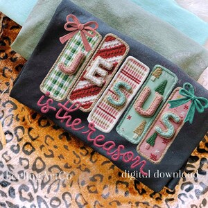 May include: A dark gray t-shirt with the word "JESUS is the reason" embroidered in pink. The word "JESUS" is spelled out with decorative rectangular patches in green, red, and pink, with bows at the top.