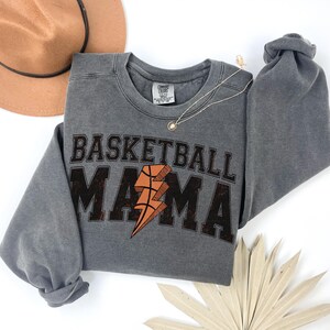 May include: Gray sweatshirt with a distressed graphic print that says "Basketball Mama" with a basketball and lightning bolt design.