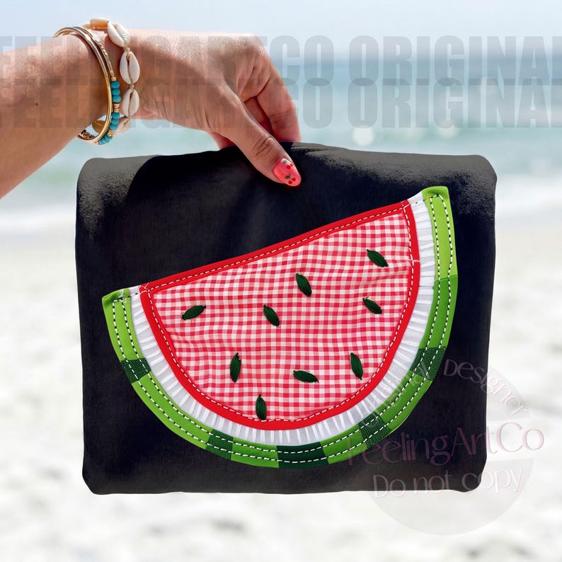 May include: Black tote bag with a watermelon slice design. The watermelon slice features a red and white checkered pattern, green rind, and small green seed accents. The bag is held up against a beach background.