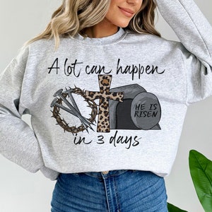 May include: A gray sweatshirt with the text "A lot can happen in 3 days" and a graphic of a cross, nails, a crown of thorns, and a stone with the text "He is risen".