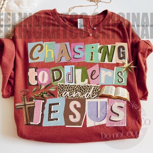 Pu&ograve; includere: Una maglietta a maniche lunghe color ruggine con le parole "Chasing Toddlers and Jesus" in stile collage. Il design include una croce, un libro aperto e una sezione con stampa leopardata. Sono visibili anche una collana e una stella dorate.