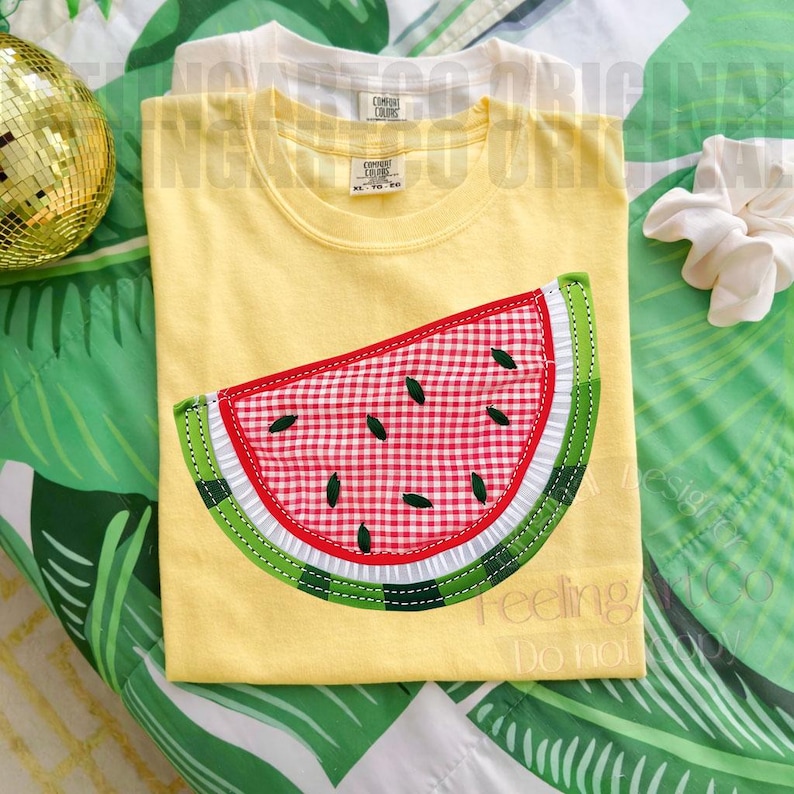 May include: Yellow t-shirt with a watermelon slice applique. The watermelon features a red and white gingham pattern, green rind, and black seeds. The shirt is part of a clothing collection.