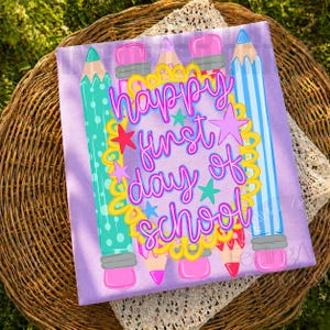 Puede incluir: Un cuadrado de tela morado claro con un marco festoneado amarillo central que contiene el texto "happy first day of school" en letra cursiva rosa brillante. El dise&ntilde;o incluye ilustraciones de l&aacute;pices coloridos en turquesa, rosa y azul con gomas.