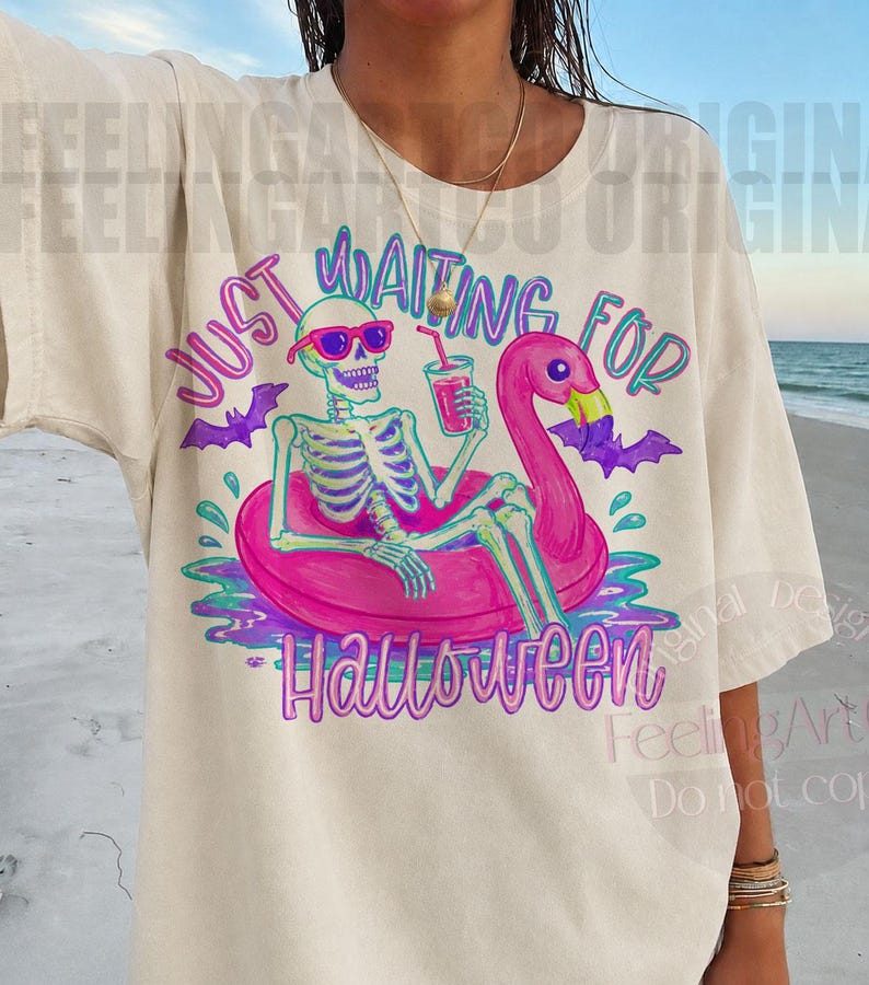 Peut inclure: T-shirt cr&egrave;me avec un squelette portant des lunettes de soleil, se pr&eacute;lassant sur un flotteur flamant rose avec une boisson. Le texte "JUST WAITING FOR HALLOWEEN" est en violet et sarcelle, avec des chauves-souris. Un design amusant et effrayant.