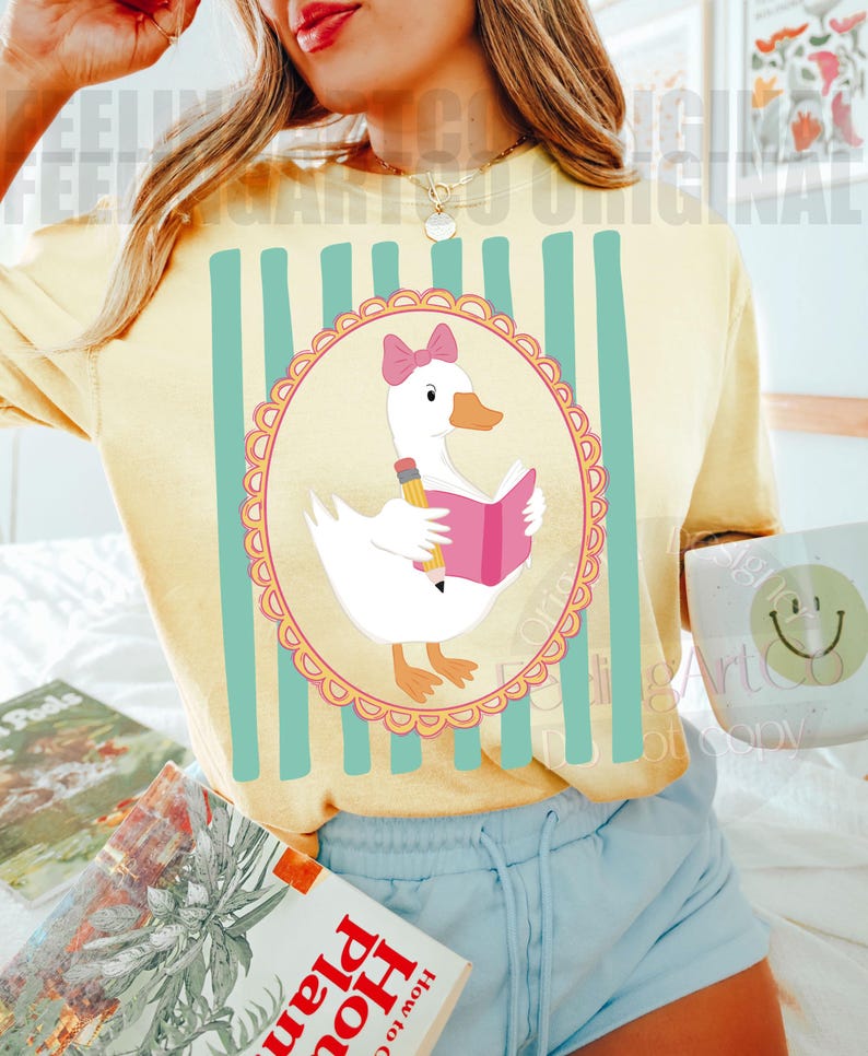 May include: Yellow t-shirt with a cartoon goose reading a book, pencil in hand, inside a pink-trimmed oval. The shirt has vertical teal stripes and the text "FEELING ART ORIGINAL".