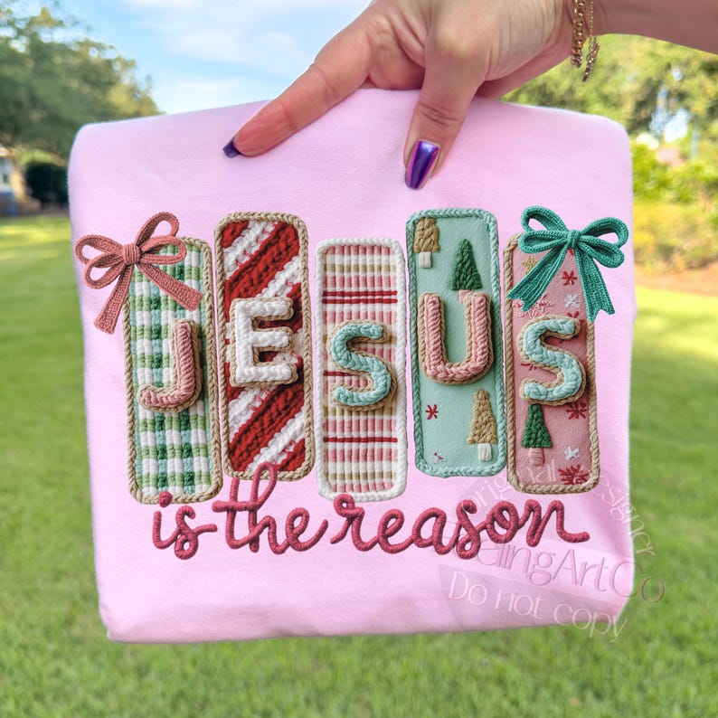 May include: A light pink sweatshirt with the embroidered words "JESUS is the reason." The letters are in a 3D style with Christmas-themed designs, including bows, candy cane stripes, and Christmas trees.