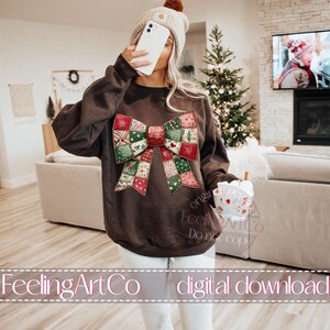 May include: A brown sweatshirt featuring a large, colorful bow design with a patchwork pattern of Christmas-themed squares. The bow has red, green, and white accents. The text "FeelingArtCo digital download" is at the bottom.