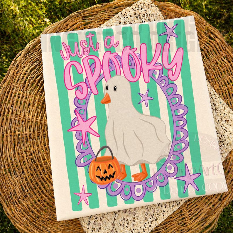 May include: A rectangular print featuring a white ghost-costumed goose inside a purple scalloped oval frame. The background has vertical teal and white stripes. The text reads just a SPOOKY in pink. A small orange jack-o'-lantern bucket is included.