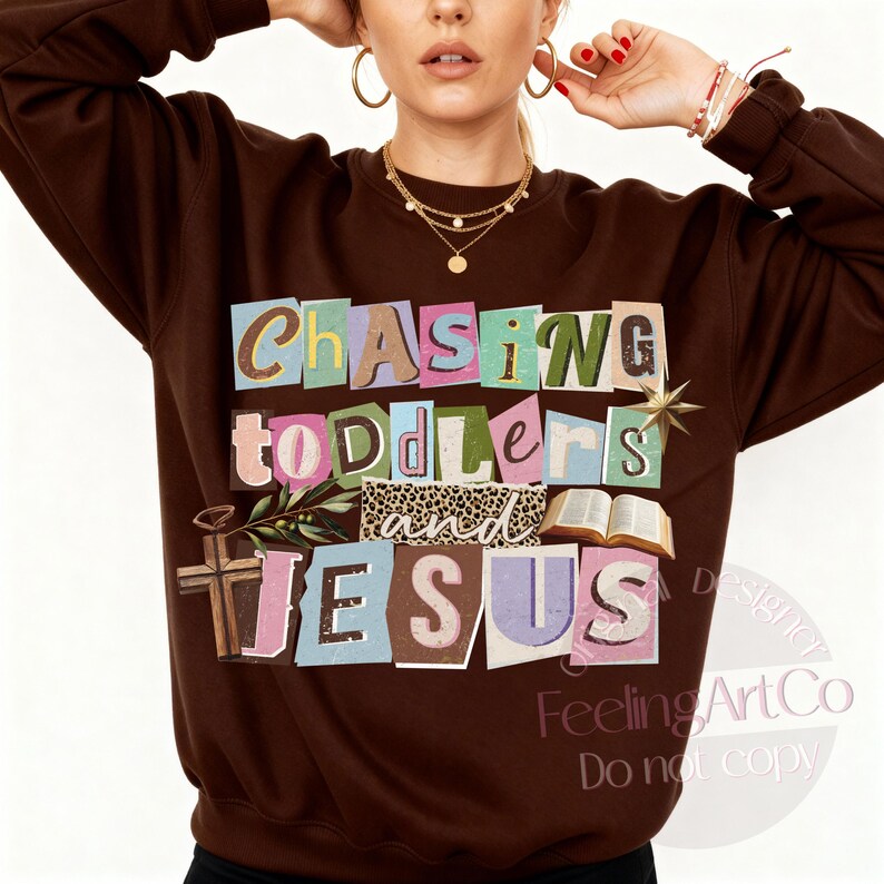 Pu&ograve; includere: Una felpa marrone con la scritta "Chasing Toddlers and Jesus" in uno stile colorato e ritagliato. Il design include una croce, un libro aperto e una stella. La felpa &egrave; uno stile comodo e casual.