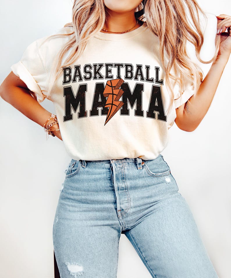May include: A white t-shirt with the text "Basketball Mama" in black with a lightning bolt and basketball graphic.
