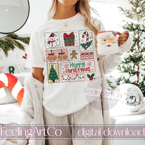 May include: White t-shirt featuring a colorful Christmas-themed design with a snowman, gift, candy cane, bells, gingerbread man, Santa faces, Christmas tree, and the words "Merry Christmas." A Santa mug is held in the hand.